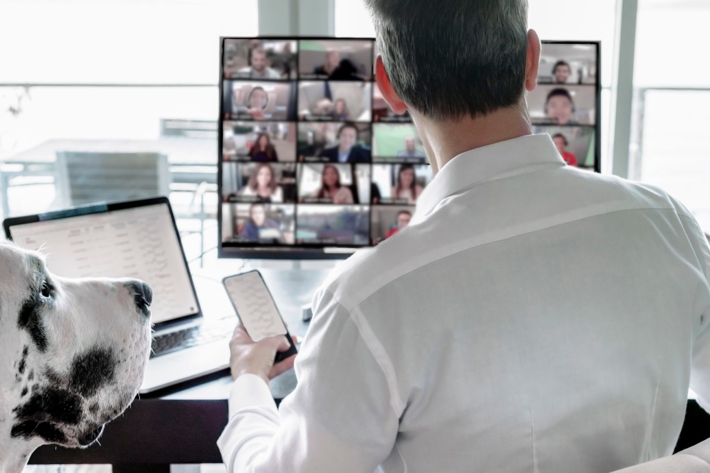 A male business professional video chats with co-workers using Zoom.